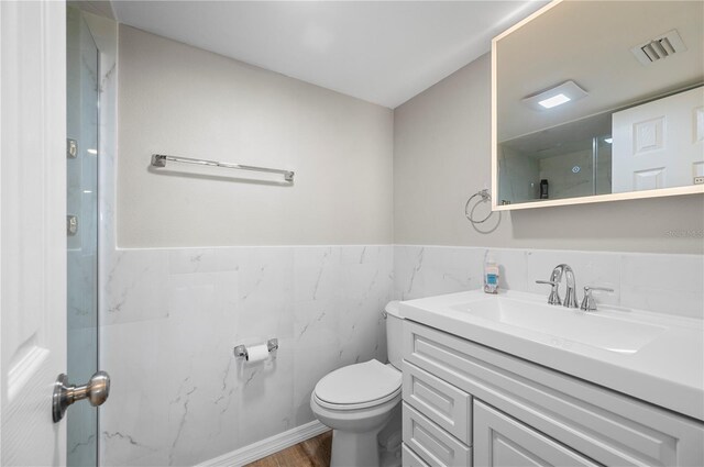 1080 Bal Harbor Blvd Unit 12C, Punta Gorda, FL 33950 - full bathroom with vanity, tile walls, toilet, wainscoting, and wood finished floors