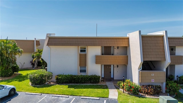 1080 Bal Harbor Blvd Unit 12C, Punta Gorda, FL 33950 - view of front of house with uncovered parking, stucco siding, and a front lawn