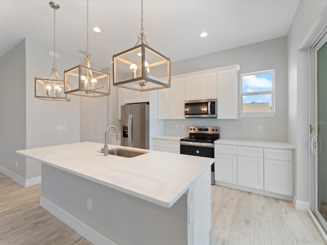 223 Australian Dr, Rotonda West, FL 33947 - kitchen with stainless steel appliances, a chandelier, light wood-style flooring, white cabinets, and a sink