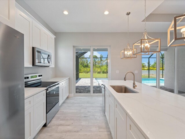 223 Australian Dr, Rotonda West, FL 33947 - kitchen with appliances with stainless steel finishes, a sink, light wood-style flooring, plenty of natural light, and recessed lighting