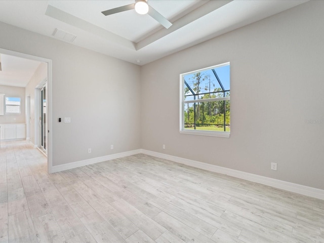 223 Australian Dr, Rotonda West, FL 33947 - empty room featuring light wood finished floors, plenty of natural light, ceiling fan, and a tray ceiling