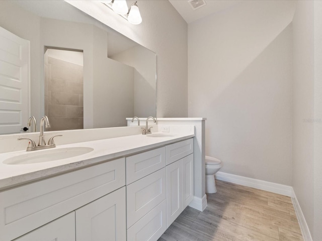 223 Australian Dr, Rotonda West, FL 33947 - bathroom with double vanity, toilet, wood finished floors, and baseboards