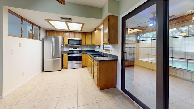 4071 Dekle Ave, North Port, FL 34286 - kitchen with stainless steel appliances, dark countertops, light tile patterned floors, and brown cabinets