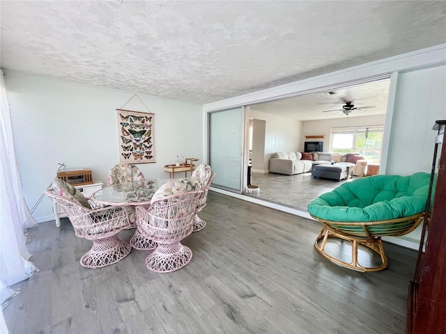 3122 Scranton St, Port Charlotte, FL 33952 - dining space featuring wood finished floors, a textured ceiling, a fireplace, baseboards, and ceiling fan