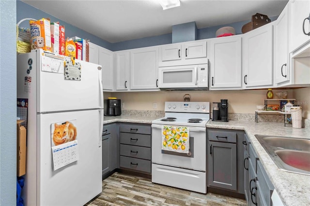 4702 Westwood Dr, Punta Gorda, FL 33982 - kitchen with white appliances, gray cabinetry, light wood finished floors, light countertops, and white cabinets