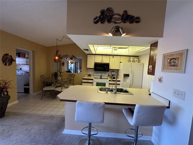 4120 SE 19th Pl Unit 202, Cape Coral, FL 33904 - kitchen with white appliances, a sink, washer / dryer, a peninsula, and a breakfast bar area