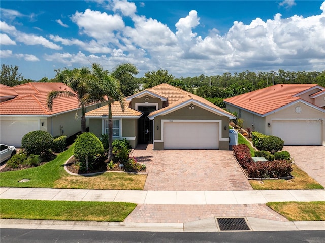 11666 Parrotfish St, Venice, FL 34292 - mediterranean / spanish-style house featuring a garage, decorative driveway, a front yard, stucco siding, and a tiled roof