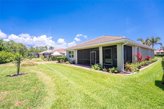 11666 Parrotfish St, Venice, FL 34292 - back of house featuring a tile roof, a lawn, a sunroom, and stucco siding
