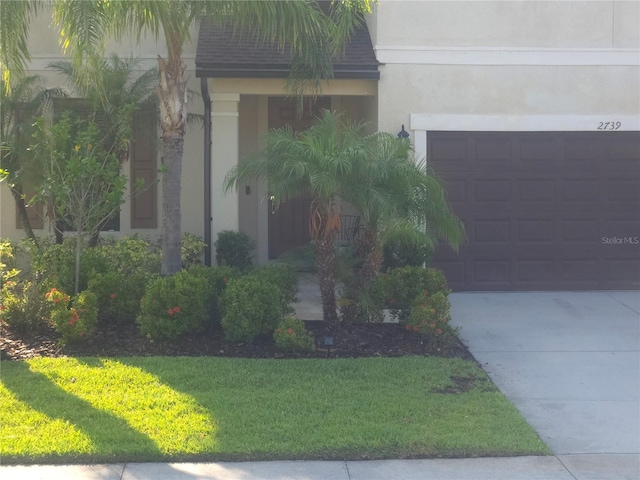 2739 Sherman Oak Dr, North Port, FL 34289 - view of front of house featuring a garage, stucco siding, a front lawn, and concrete driveway