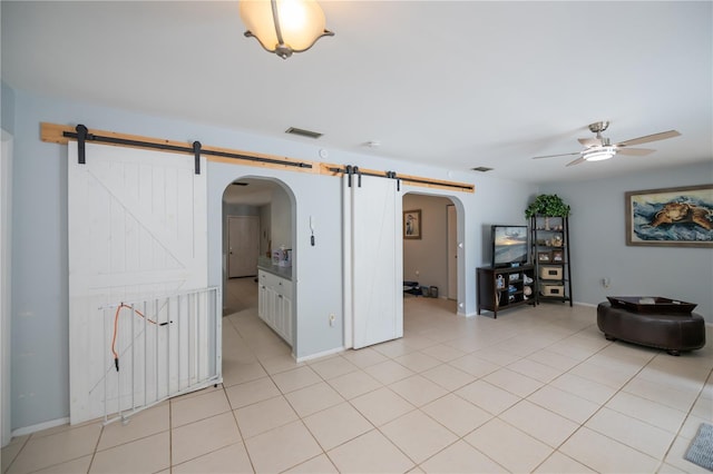 7231 Elyton Dr, North Port, FL 34287 - unfurnished room featuring a barn door, arched walkways, ceiling fan, light tile patterned flooring, and baseboards