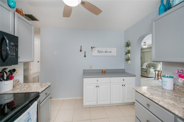 7231 Elyton Dr, North Port, FL 34287 - kitchen featuring ceiling fan, black microwave, arched walkways, light tile patterned floors, and baseboards