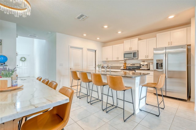 111 Rain Lily Ave, Spring Hill, FL 34609 - kitchen featuring stainless steel appliances, a kitchen breakfast bar, white cabinetry, recessed lighting, and a kitchen island with sink