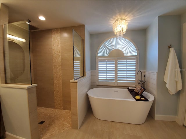 4216 Bur St, Port Charlotte, FL 33948 - bathroom with a freestanding bath, a walk in shower, a chandelier, wainscoting, and tile patterned flooring