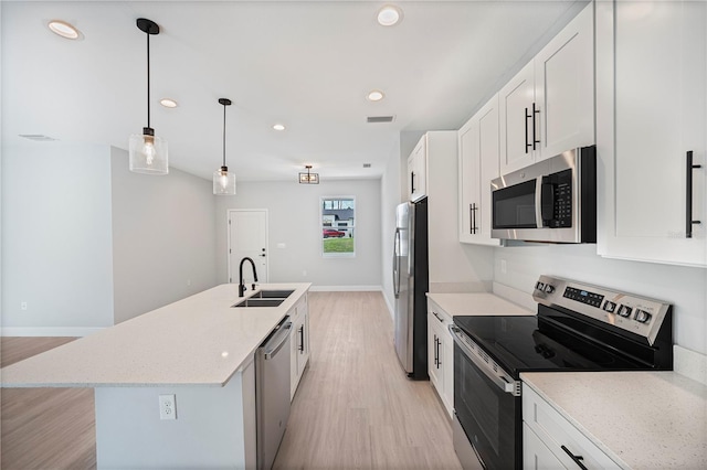 17197 Russell Ave, Port Charlotte, FL 33954 - kitchen featuring appliances with stainless steel finishes, a sink, light wood-style flooring, a center island with sink, and white cabinets