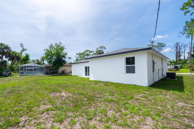 17197 Russell Ave, Port Charlotte, FL 33954 - back of house featuring central AC, a yard, and stucco siding