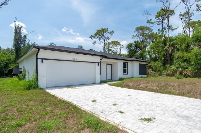 16218 Chamberlain Blvd, Port Charlotte, FL 33954 - view of front facade featuring stucco siding, a garage, decorative driveway, and central AC