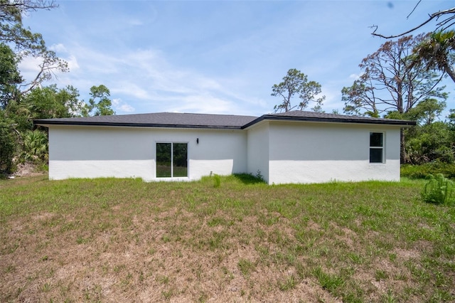 16218 Chamberlain Blvd, Port Charlotte, FL 33954 - rear view of house featuring stucco siding and a lawn