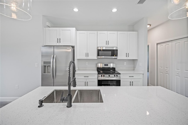 16218 Chamberlain Blvd, Port Charlotte, FL 33954 - kitchen featuring appliances with stainless steel finishes, a sink, white cabinets, recessed lighting, and light stone countertops