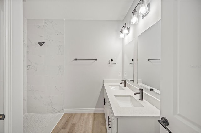 16218 Chamberlain Blvd, Port Charlotte, FL 33954 - bathroom featuring double vanity, a tile shower, baseboards, and wood finished floors
