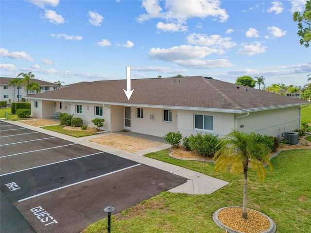 12538 SW Kingsway Cir Unit 1503, Lake Suzy, FL 34269 - exterior space with central AC unit, a shingled roof, stucco siding, a front lawn, and uncovered parking