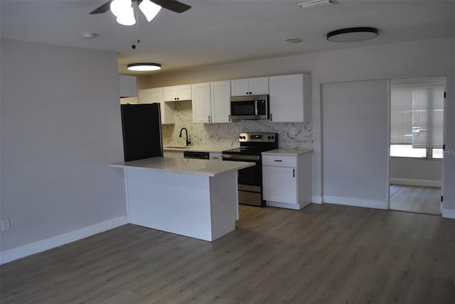 21275 Austin Ave, Port Charlotte, FL 33952 - kitchen featuring stainless steel appliances, white cabinetry, tasteful backsplash, light countertops, and wood finished floors
