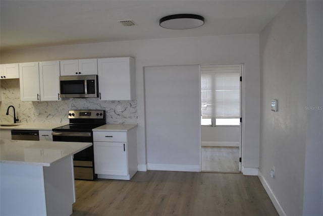 21275 Austin Ave, Port Charlotte, FL 33952 - kitchen featuring stainless steel appliances, a sink, decorative backsplash, white cabinets, and light countertops