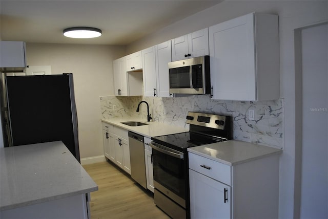 21275 Austin Ave, Port Charlotte, FL 33952 - kitchen with appliances with stainless steel finishes, a sink, decorative backsplash, light wood-style floors, and white cabinets