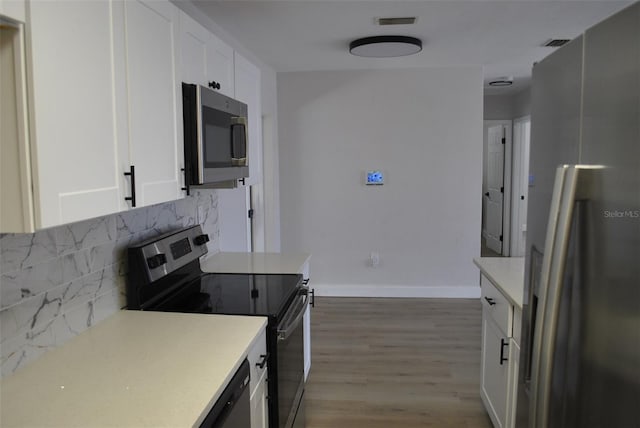 21275 Austin Ave, Port Charlotte, FL 33952 - kitchen featuring appliances with stainless steel finishes, tasteful backsplash, white cabinets, wood finished floors, and light countertops