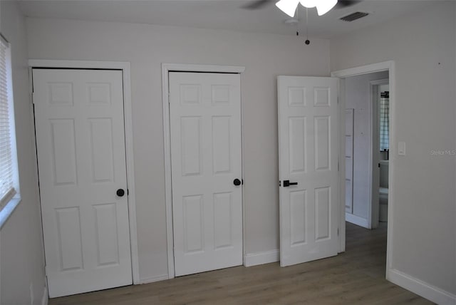 21275 Austin Ave, Port Charlotte, FL 33952 - unfurnished bedroom with wood finished floors, baseboards, ceiling fan, and two closets