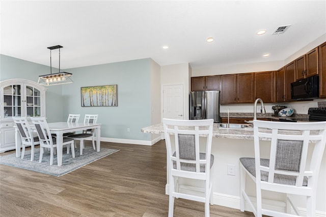 8866 Tuscany Isles Dr, Punta Gorda, FL 33950 - kitchen with black microwave, stainless steel fridge with ice dispenser, dark brown cabinetry, baseboards, and light wood finished floors