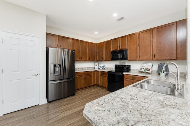 8866 Tuscany Isles Dr, Punta Gorda, FL 33950 - kitchen featuring black appliances, a sink, light wood-style flooring, light countertops, and brown cabinetry