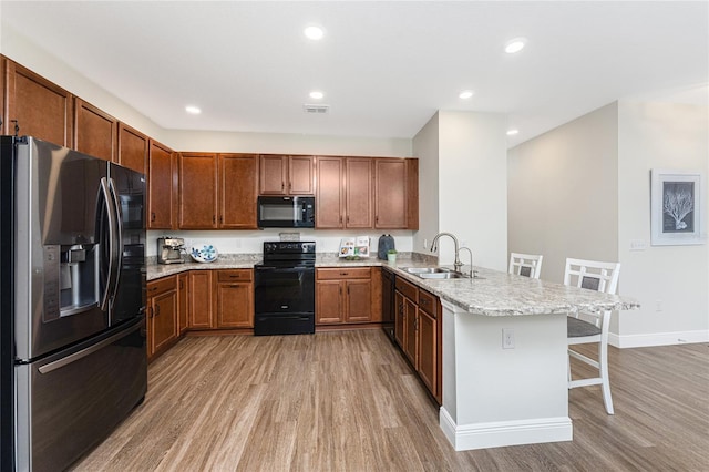8866 Tuscany Isles Dr, Punta Gorda, FL 33950 - kitchen with black appliances, a sink, a peninsula, light wood-type flooring, and recessed lighting