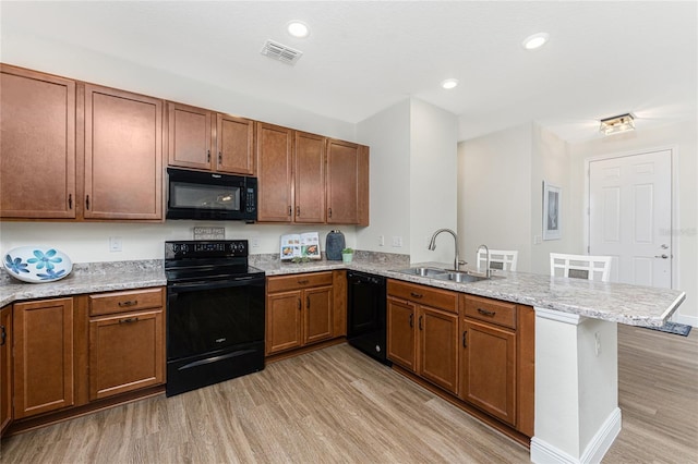 8866 Tuscany Isles Dr, Punta Gorda, FL 33950 - kitchen featuring black appliances, a sink, a peninsula, light wood-style flooring, and brown cabinetry