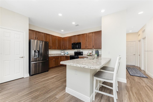 8866 Tuscany Isles Dr, Punta Gorda, FL 33950 - kitchen featuring black appliances, a sink, a peninsula, light countertops, and light wood-type flooring