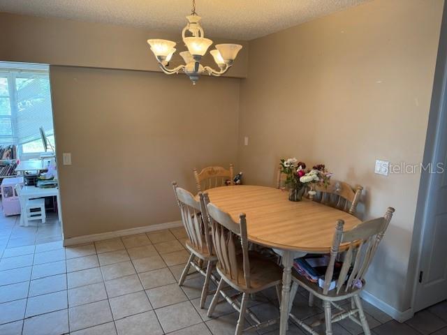 8158 Trionfo Ave, North Port, FL 34287 - dining space with a chandelier, light tile patterned floors, baseboards, and a textured ceiling