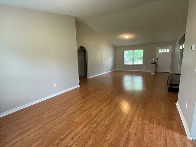 41 Brewster Ln, Palm Coast, FL 32137 - unfurnished living room with wood finished floors, baseboards, lofted ceiling, and arched walkways