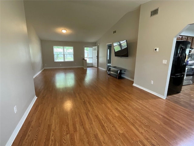 41 Brewster Ln, Palm Coast, FL 32137 - unfurnished living room featuring wood finished floors, arched walkways, baseboards, and high vaulted ceiling