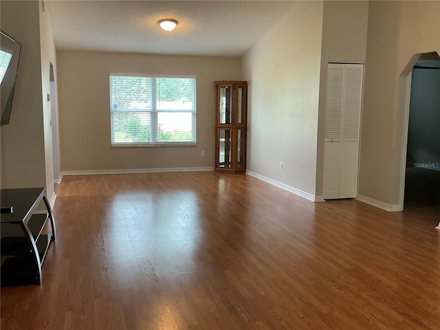 41 Brewster Ln, Palm Coast, FL 32137 - unfurnished living room featuring arched walkways, wood finished floors, and baseboards