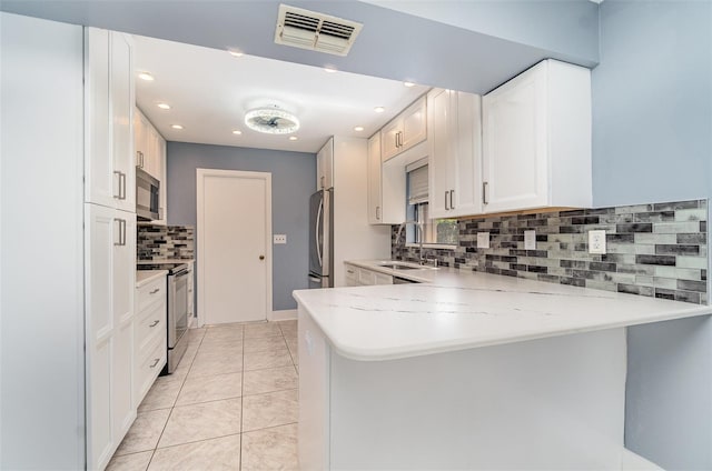 541 Wekiva River Ct Unit 94, Englewood, FL 34223 - kitchen featuring stainless steel appliances, a sink, a peninsula, decorative backsplash, and white cabinets