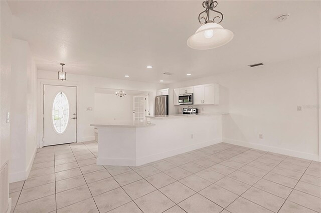 3129 Buttonwood Pl, Punta Gorda, FL 33950 - kitchen featuring stainless steel appliances, light tile patterned floors, a peninsula, white cabinets, and recessed lighting