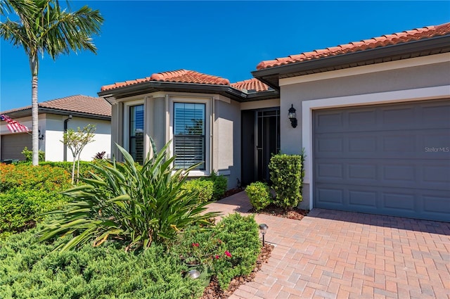 1470 Hyssop Loop, North Port, FL 34289 - view of front of property featuring a tiled roof, a garage, stucco siding, and decorative driveway