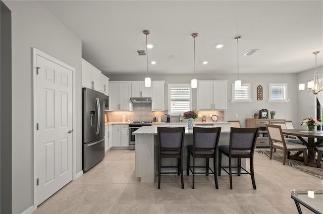 1470 Hyssop Loop, North Port, FL 34289 - kitchen with stainless steel appliances, under cabinet range hood, tasteful backsplash, white cabinetry, and healthy amount of natural light