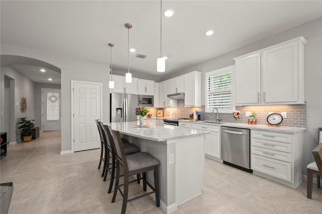 1470 Hyssop Loop, North Port, FL 34289 - kitchen with appliances with stainless steel finishes, arched walkways, a kitchen bar, backsplash, and white cabinets