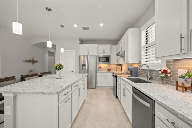 1470 Hyssop Loop, North Port, FL 34289 - kitchen with appliances with stainless steel finishes, a sink, a center island, tasteful backsplash, and white cabinetry