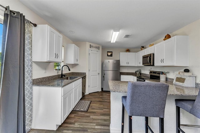 3799 Laredo Ave, North Port, FL 34288 - kitchen featuring stainless steel appliances, a sink, a peninsula, dark wood finished floors, and white cabinetry