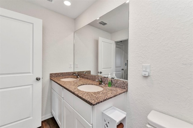 3799 Laredo Ave, North Port, FL 34288 - bathroom with double vanity, a textured wall, toilet, and wood finished floors