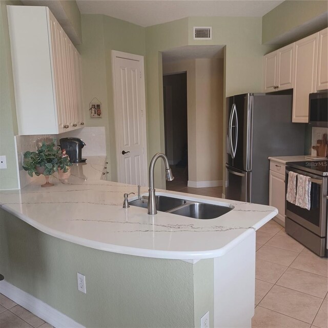 96 Vivante Blvd Unit 9622, Punta Gorda, FL 33950 - kitchen featuring stainless steel appliances, a sink, a peninsula, light tile patterned floors, and light stone countertops