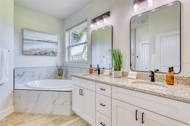 122 Arrow Ln, Rotonda West, FL 33947 - bathroom featuring double vanity, wood finished floors, and a bath