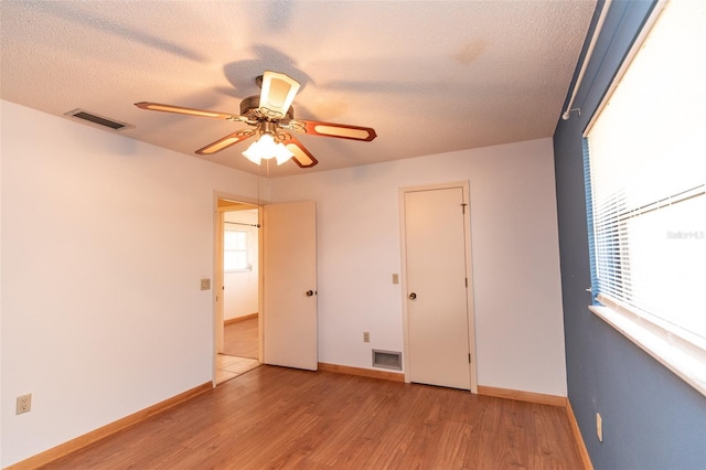 238 Mark Twain Ln, Rotonda West, FL 33947 - unfurnished bedroom with wood finished floors, multiple windows, a textured ceiling, baseboards, and a ceiling fan