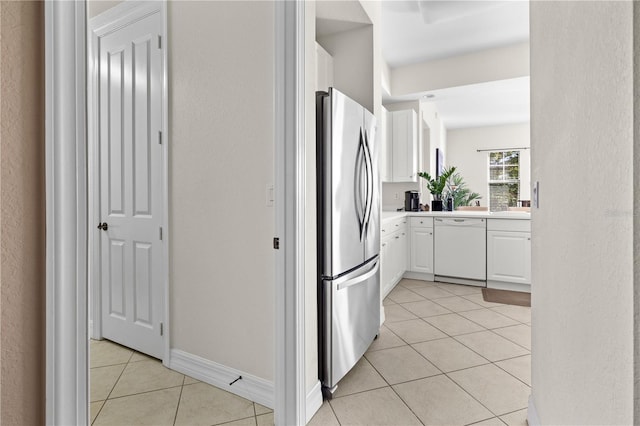 99 Vivante Blvd Unit 303, Punta Gorda, FL 33950 - kitchen with dishwasher, freestanding refrigerator, light tile patterned flooring, white cabinets, and light countertops